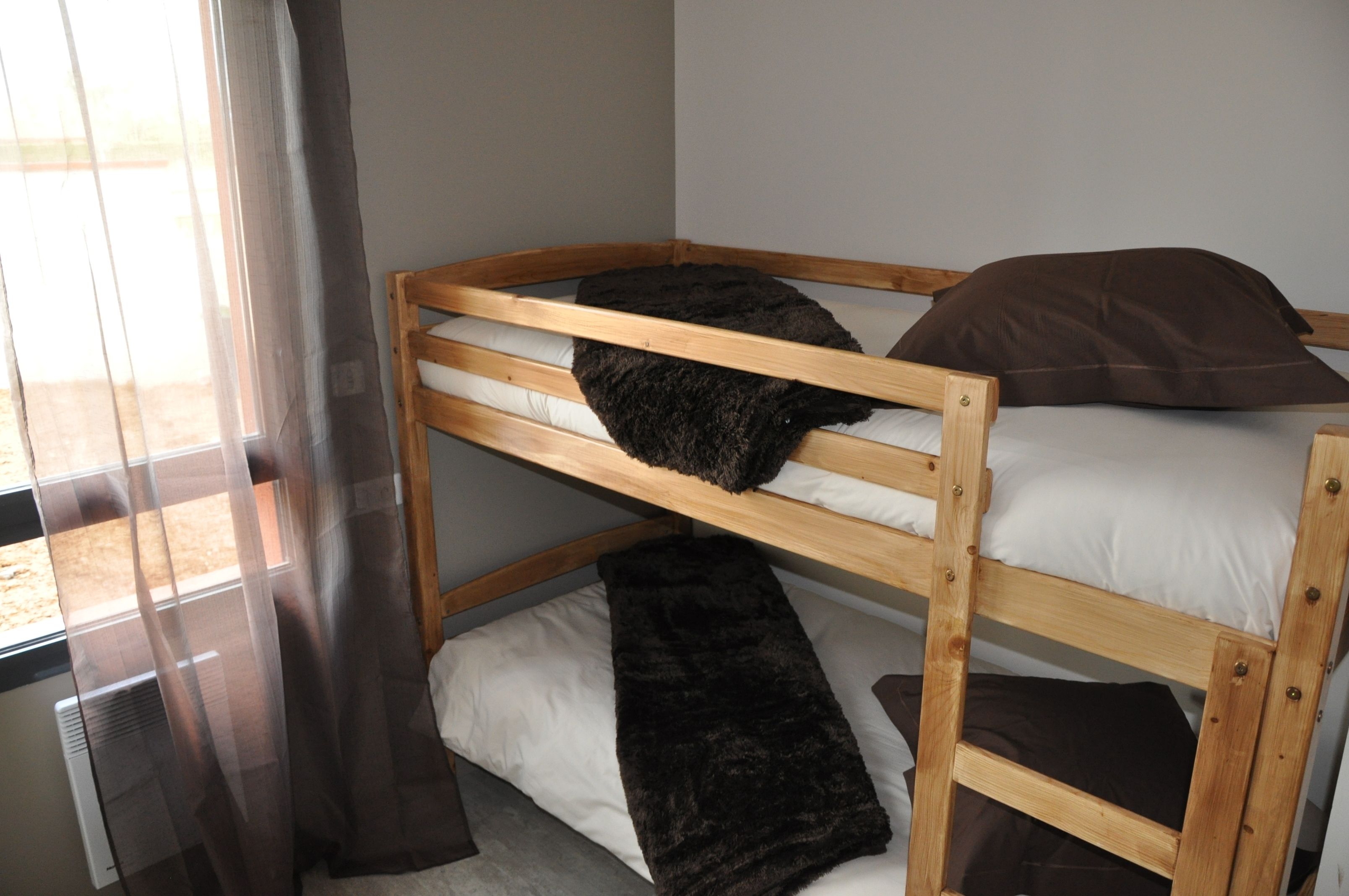 A bunk bed with two levels, each with a pillow and a blanket.