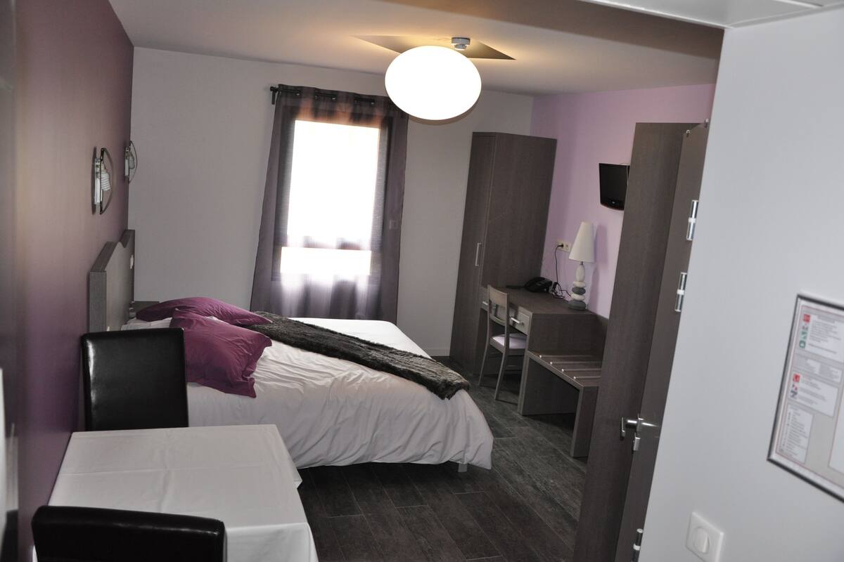 Ein Hotelzimmer mit Bett, Schreibtisch, Stuhl und einem kleinen Tisch.