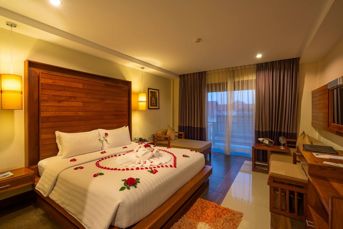 Habitación de hotel con una cama grande, un escritorio y vistas al exterior.