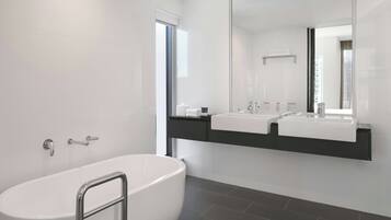 A modern bathroom with a freestanding bathtub, a large mirror, and a dual sink vanity.
