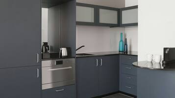 A modern kitchen with grey cabinets, a stainless steel oven, and a sink.