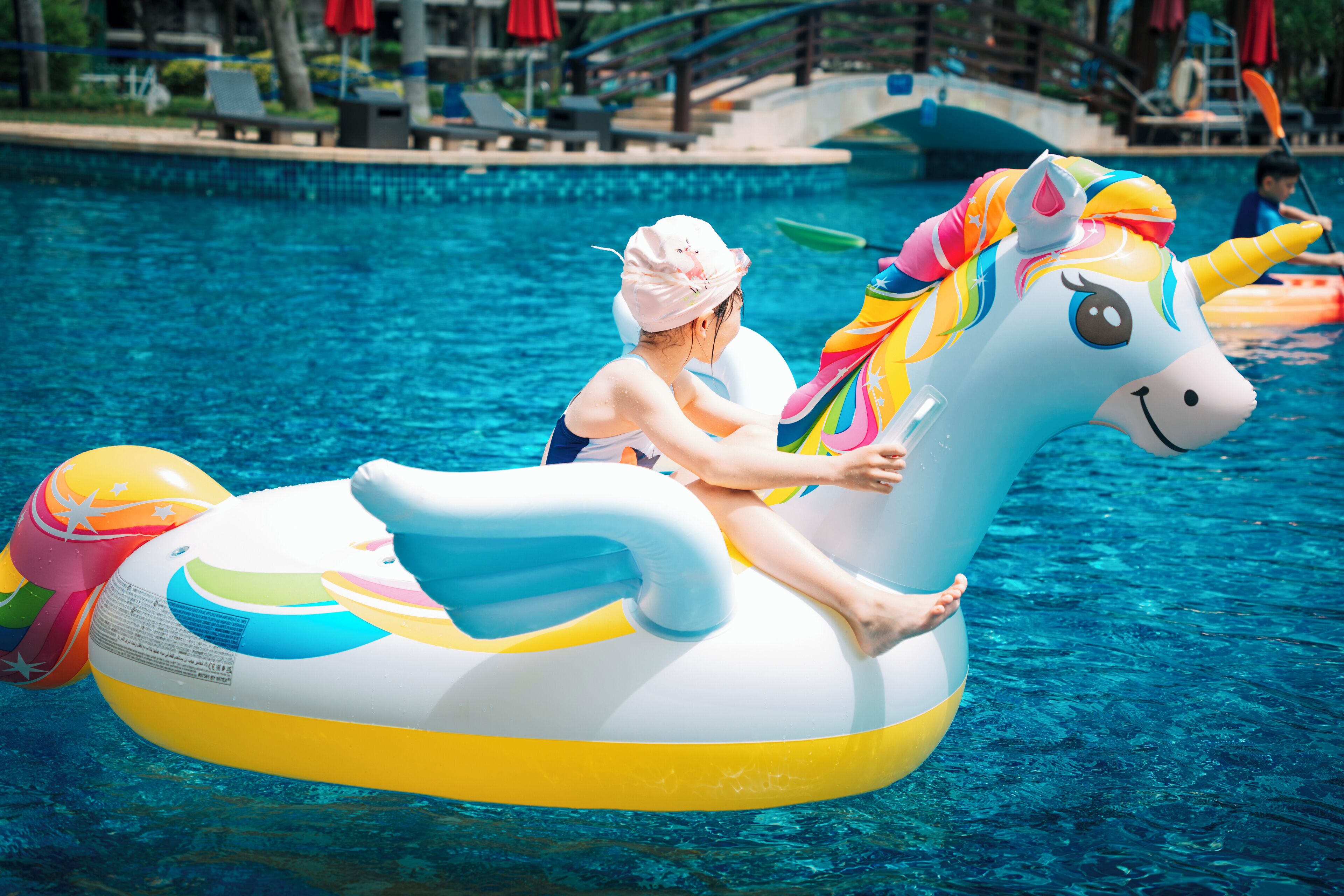 A person on a unicorn float in a swimming pool.
