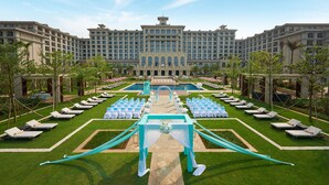 A large hotel with a central courtyard, rows of lounge chairs, and a swimming pool. - Hilton Haikou Meilan (Haikou)