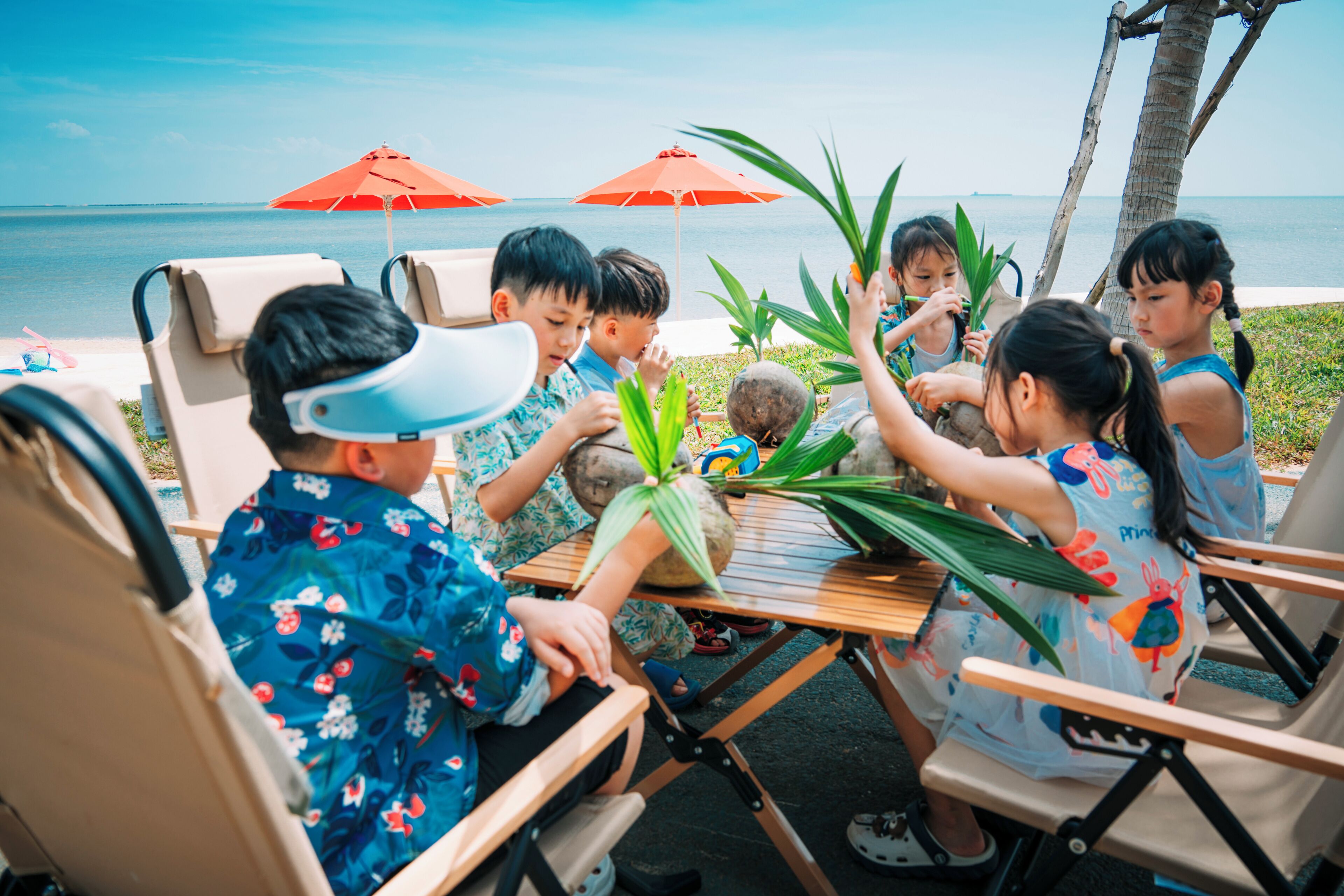 A group of people seated around a wooden table outdoors with a view of the sea.