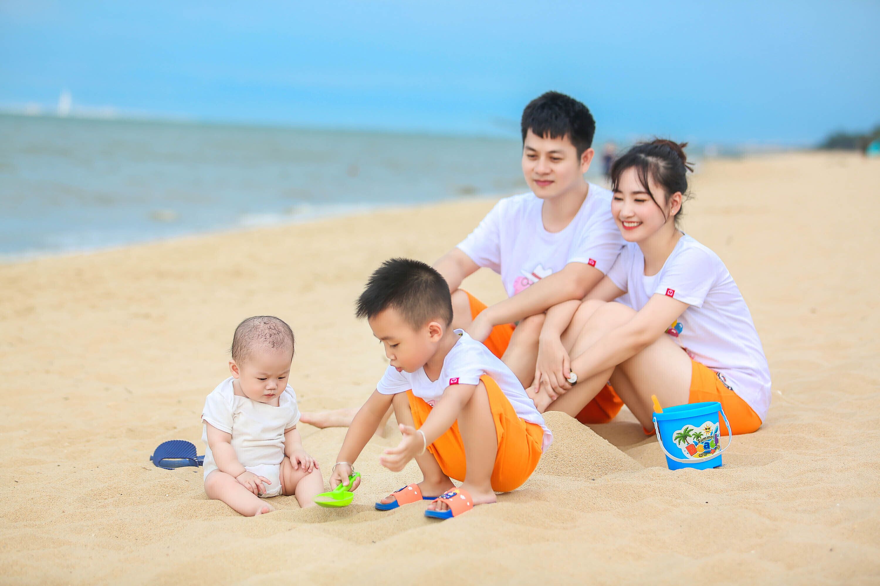 A family of four on a sandy beach with a clear sky.