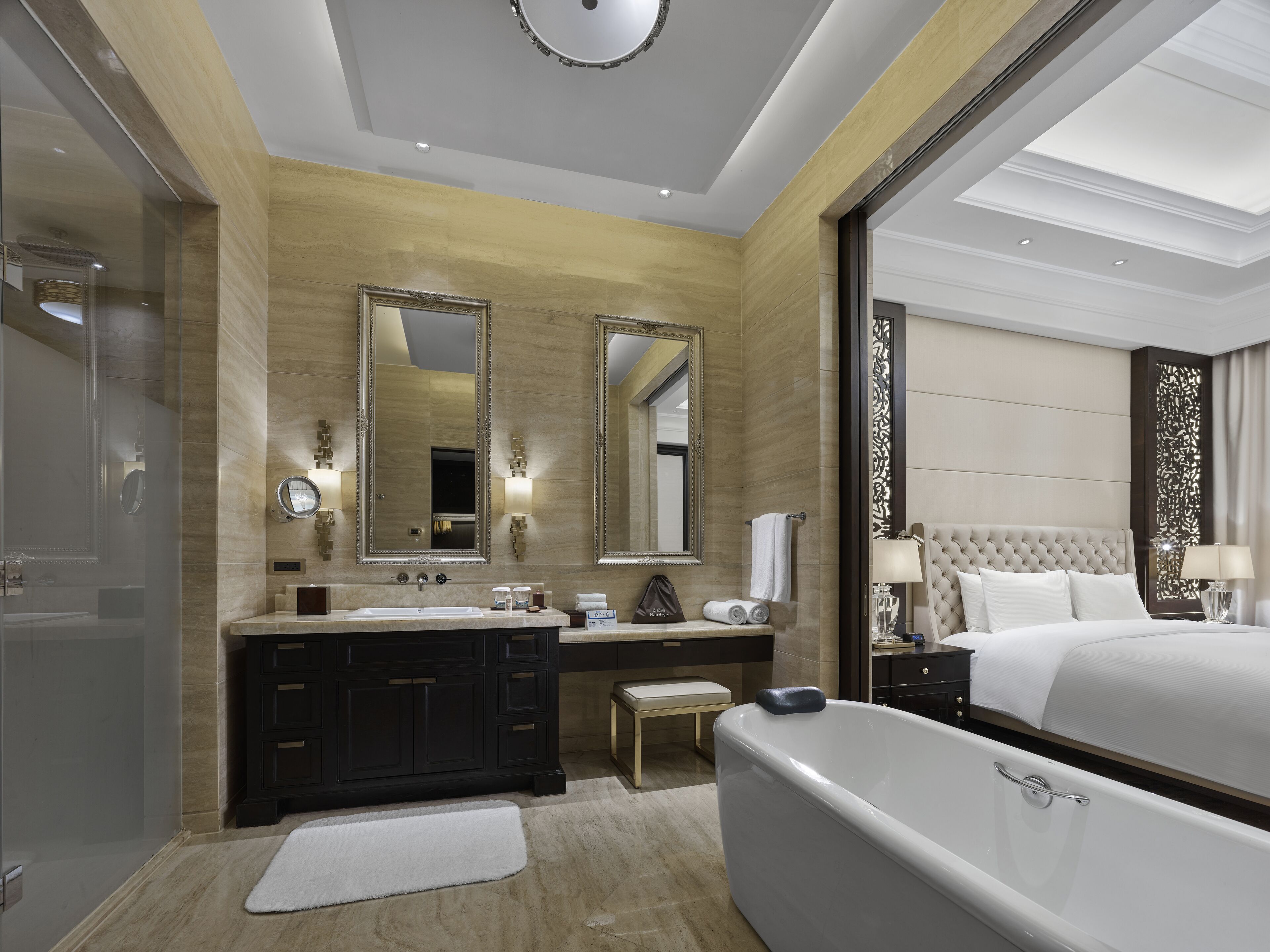 Un baño de hotel moderno con bañera, lavamanos doble y un espejo grande.