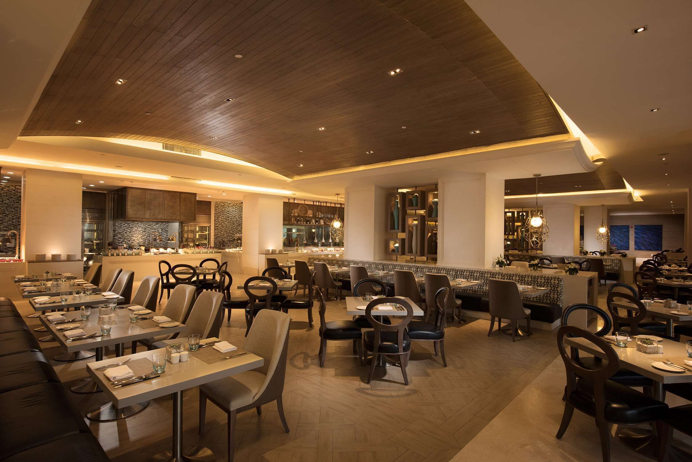 Un ristorante moderno con una lunga sala da pranzo, posti a sedere disposti a bancada e un bancone bar.