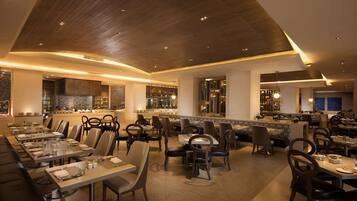 A modern restaurant with a long dining area, booths, and a bar.