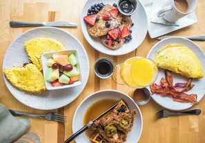 A breakfast table with various dishes including waffles, eggs, and fruit.