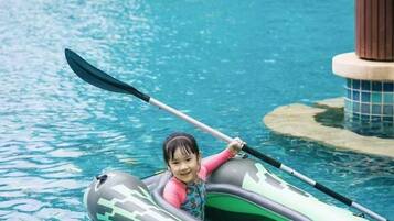 Un niño en un kayak inflable verde con la etiqueta 'CHALLENGER' en una piscina.