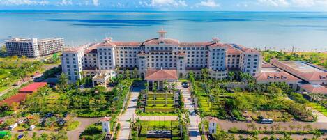 A large hotel with multiple buildings, a central courtyard, and a view of the ocean.