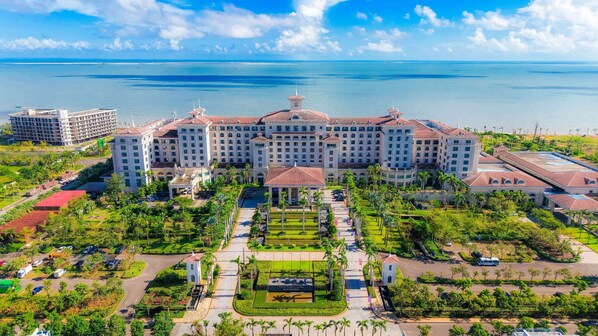 A large hotel with multiple buildings, a central courtyard, and a view of the ocean.
