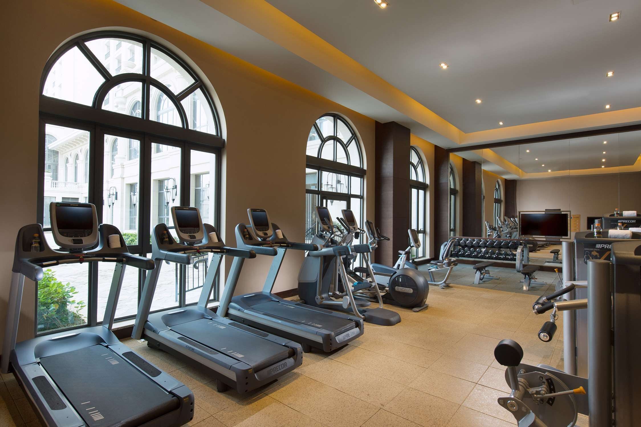 Un gimnasio con cintas de correr, máquinas elípticas y equipo de pesas.