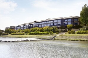 A modern building with a flat roof, large windows, and a landscaped area with a water feature in front.