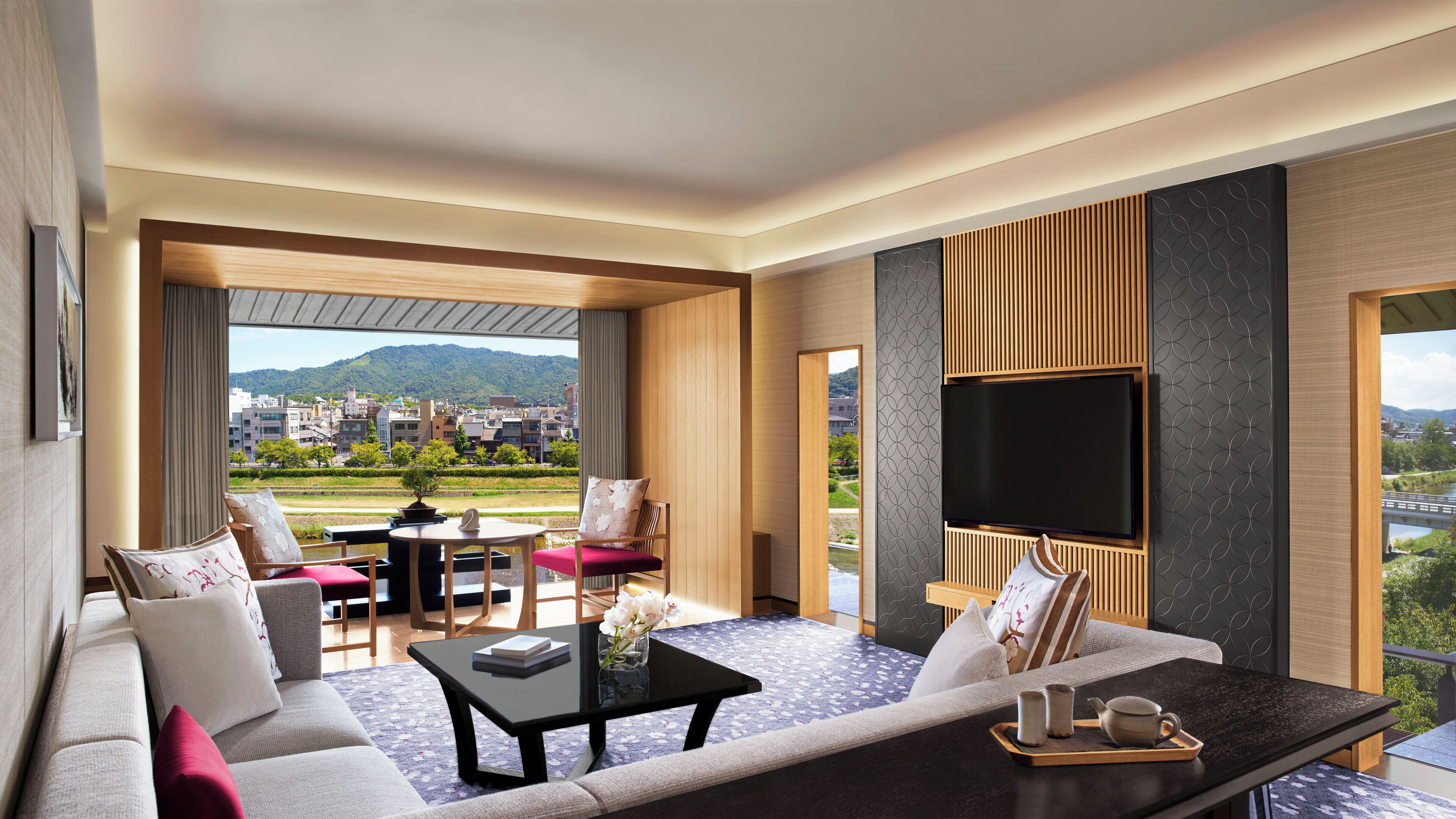 A modern hotel room with a sofa, a dining table, and a TV.