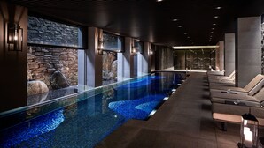 A modern indoor pool with a glass bottom, stone walls, and lounge chairs along the side. - The Ritz-Carlton, Kyoto (Kyoto)