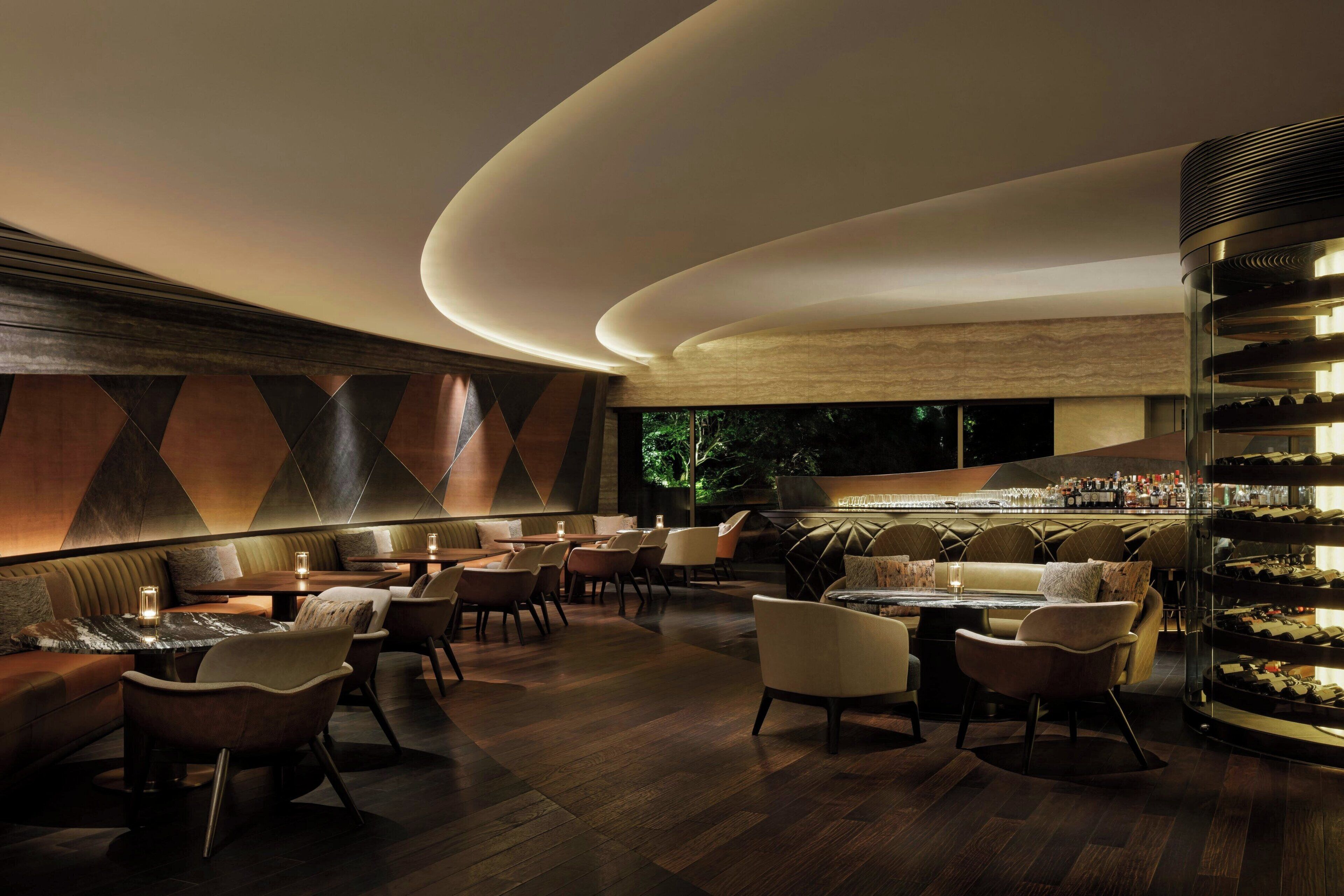 A modern bar area with seating and a wine display.