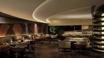 A modern bar area with seating and a wine display.