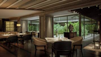 A modern restaurant with a wooden ceiling, large windows, and a view of greenery outside.