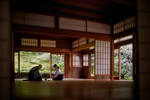 A traditional Japanese room with tatami flooring, sliding doors, and a view of a garden.