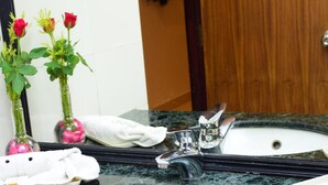 Un baño con lavamanos de mármol, un espejo y un perchero para toallas.