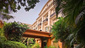 Entrada de hotel con un corredor cubierto, rodeada de exuberante vegetación y palmeras.