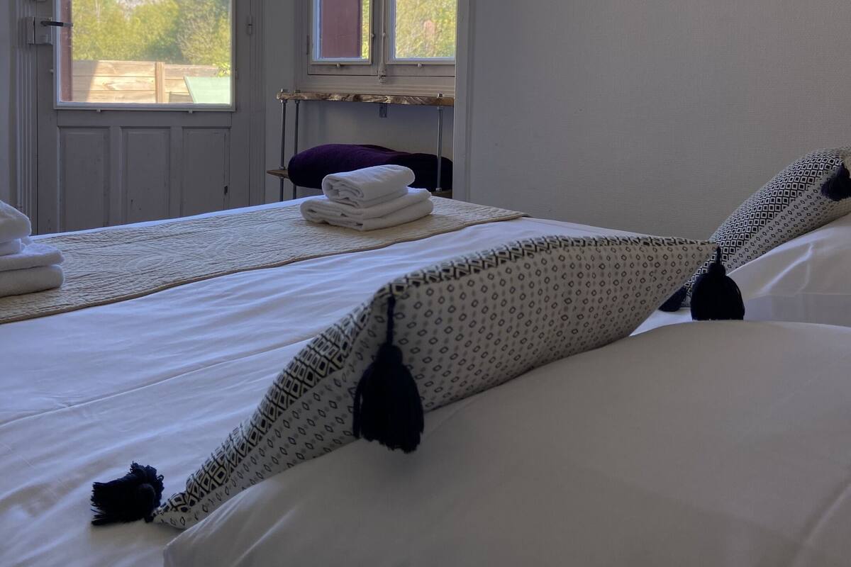 Une chambre à coucher avec un lit, une grande horloge murale et deux fenêtres.