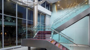 A modern interior with a glass staircase, a central metallic spiral structure, and large windows. - Hyatt House Washington DC / Downtown / Convention Center (Washington)