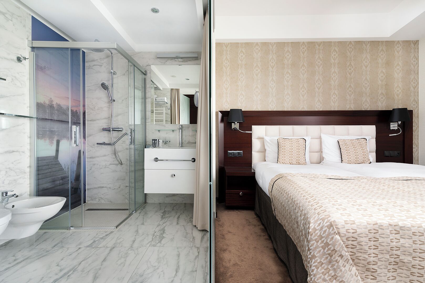 A modern bathroom with a glass shower enclosure, a white sink, and a marble floor. The bedroom features a large bed with patterned bedding, a headboard with wall-mounted lamps, and a carpeted floor.