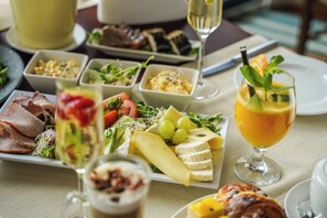 A table set with various dishes including meats, cheeses, fruits, and a glass of juice.