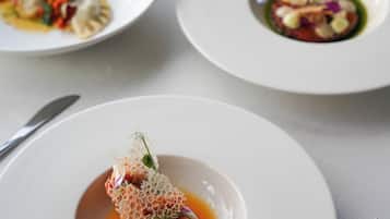 A dining table with three white plates of food, each with a different dish.
