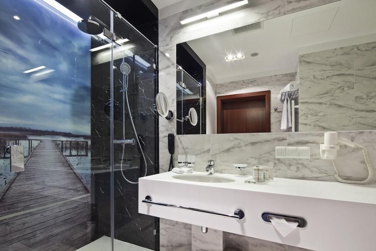 A modern bathroom with a glass-enclosed shower, a marble vanity, and a large mirror.