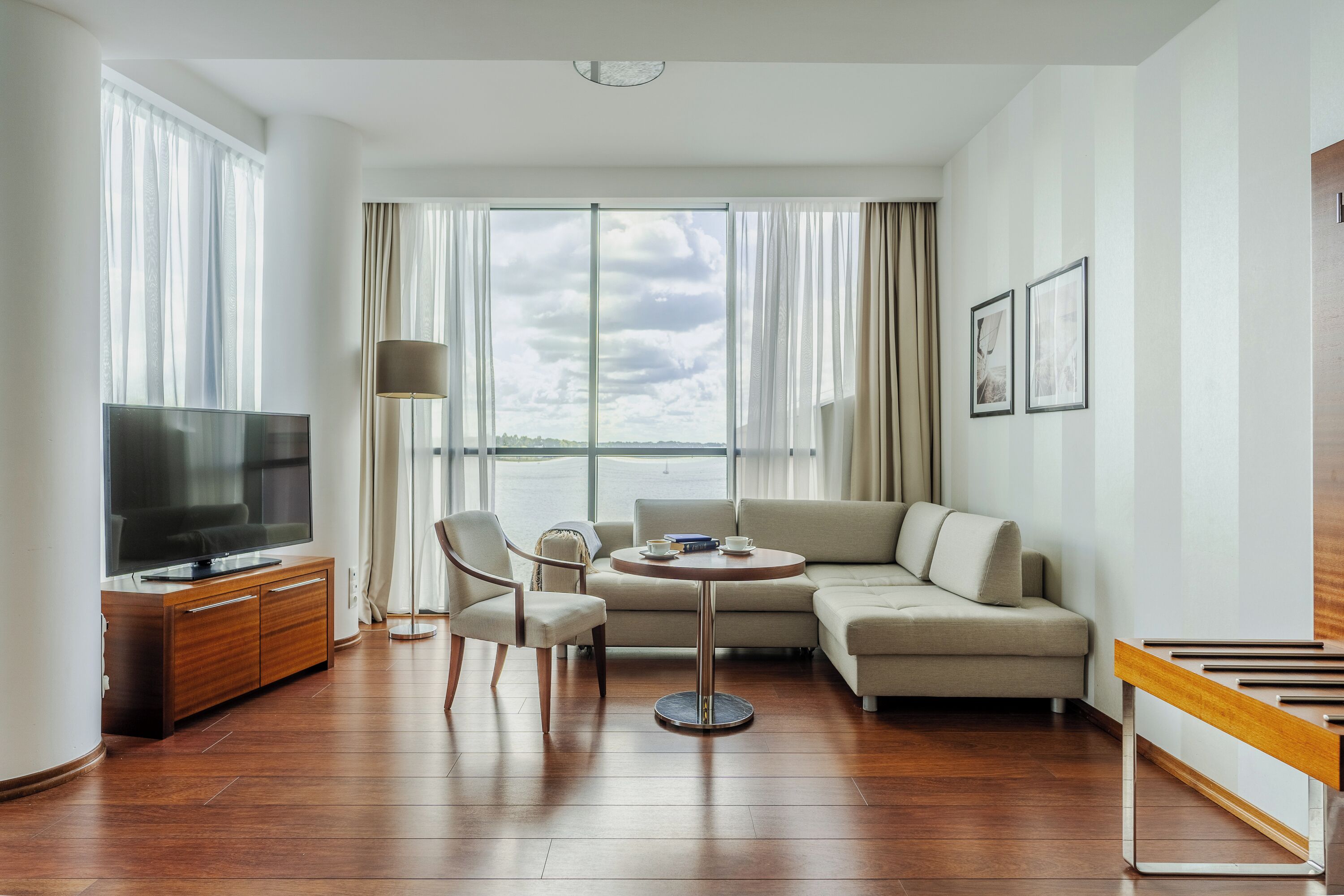 A modern living room with a large flat-screen TV, a round coffee table, a sofa, and a dining table.