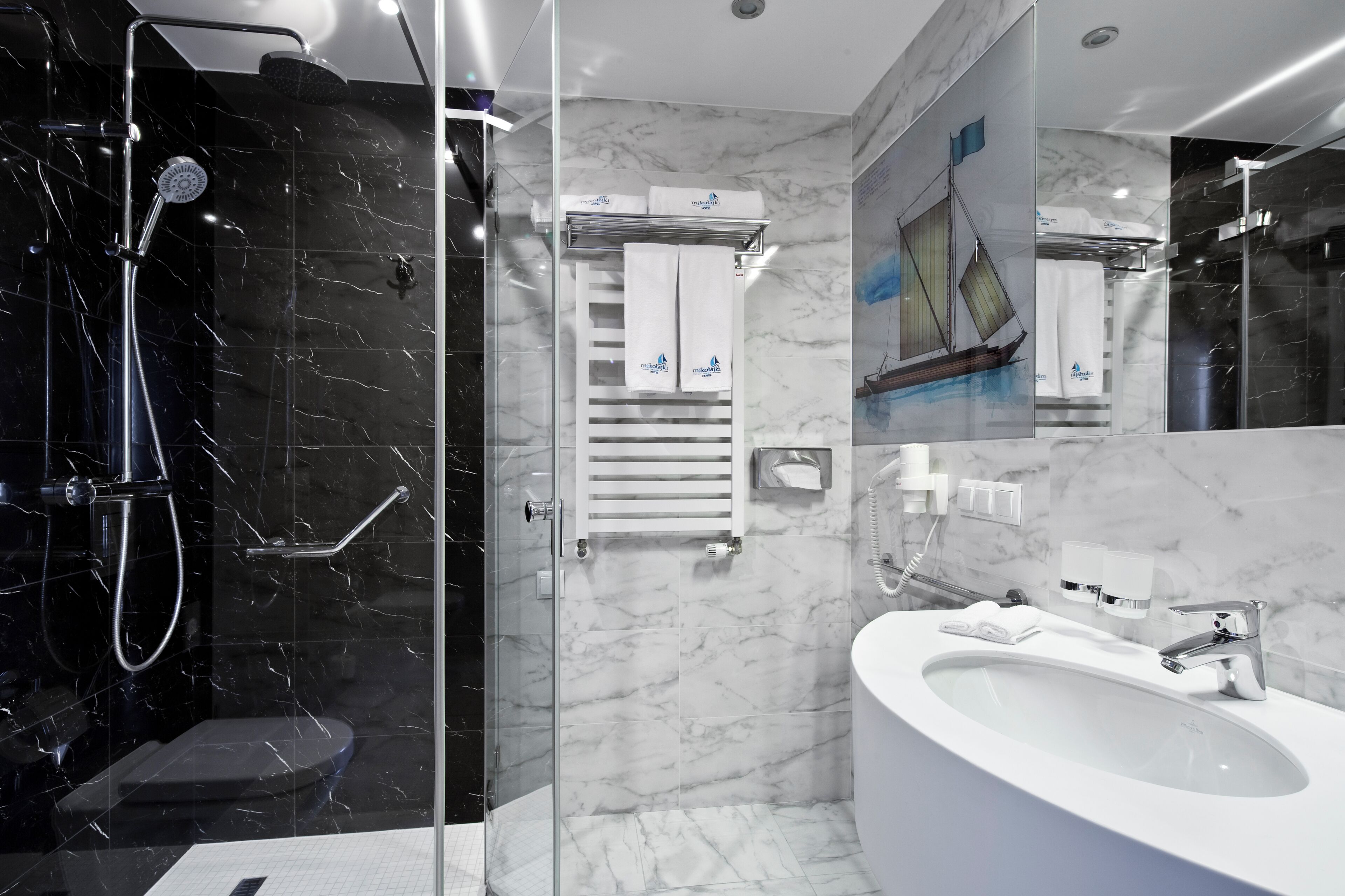 A modern bathroom with a glass-enclosed shower, a white sink, and a towel rack.
