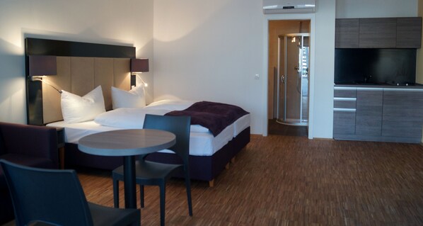 A modern hotel room with a bed, a round table, and a TV. - Goethe Business Hotel by Trip Inn (Frankfurt)