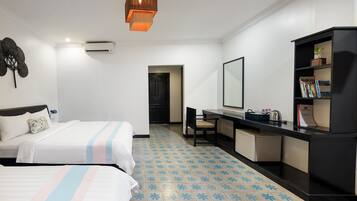 A hotel room with two beds, a desk, a bookshelf, and a bathroom visible through an open door.