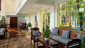 A spacious lobby with a high ceiling, large windows, and a seating area with a wooden sofa and chairs. - La Residence WatBo Hotel (Siem Reap)