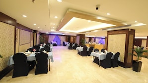 A banquet hall with multiple tables set for dining, a stage area, and a reception desk. - Concorde Mina Hotel (Makkah)