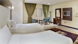 A hotel room with two beds, a desk, a chair, a TV, and a mirror. - Concorde Mina Hotel (Makkah)