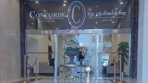 A hotel entrance with a marble floor, a reception desk, and a decorative vase with flowers. - Concorde Mina Hotel (Makkah)