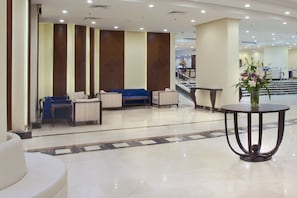 A hotel lobby with a reception desk, seating area, and a staircase leading to upper floors. - Concorde Mina Hotel (Makkah)