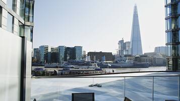 Un edificio moderno con vistas al horizonte de la ciudad, incluyendo The Shard, y un río con barcos.
