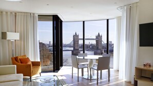 A modern hotel room with a large window offering a view of a bridge and cityscape. - Cheval Three Quays at The Tower of London (London)