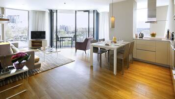 A modern living room with a sofa, TV, and dining area with a view of the city.