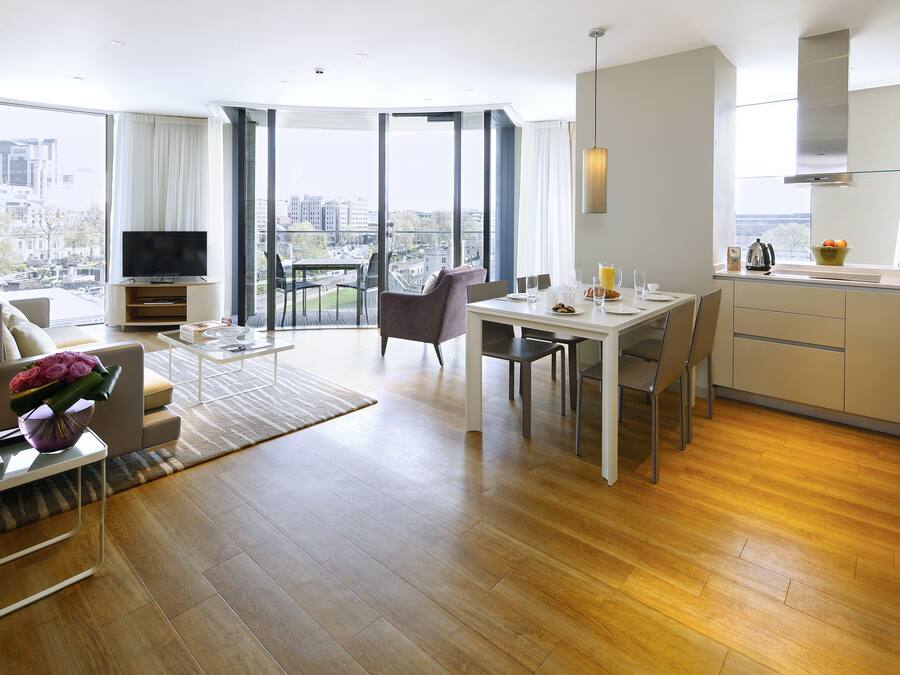 A modern living room with a sofa, TV, and dining area with a view of the city.