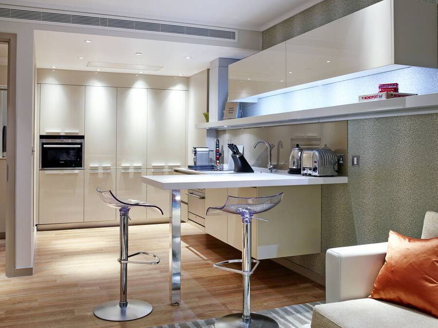 Una cocina moderna con una isla central, electrodomésticos de acero inoxidable y una zona de estar con dos taburetes de bar.