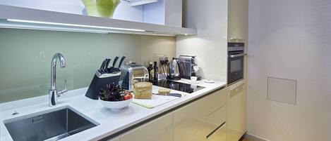 A modern kitchen with a stainless steel sink, a toaster, a kettle, and a coffee maker.