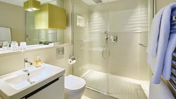 Une salle de bain moderne avec une douche à parois de verre, un lavabo blanc et des toilettes.
