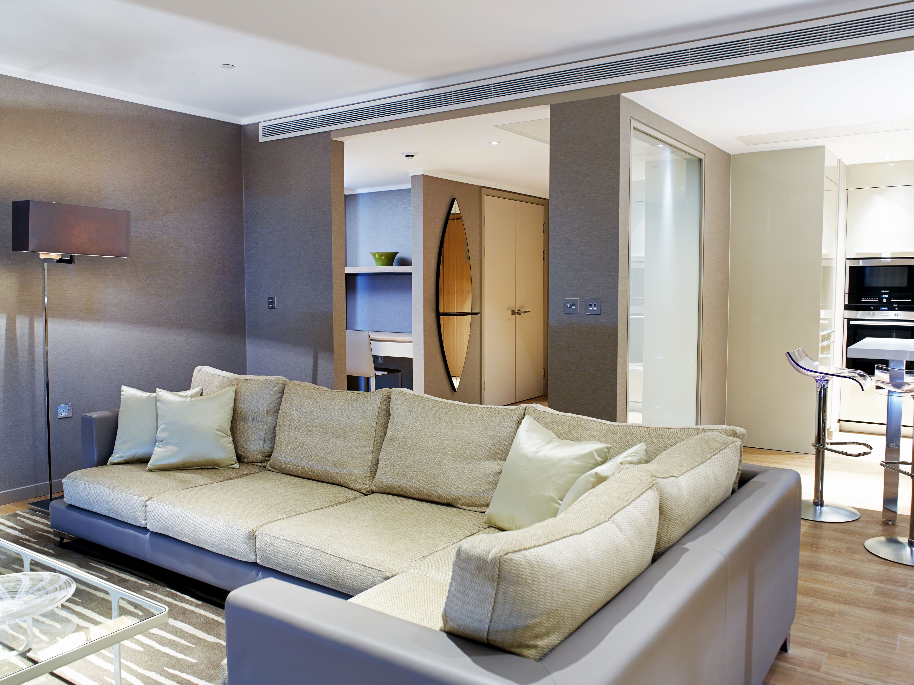 A modern living room with a sectional sofa, a floor lamp, and a glass coffee table.