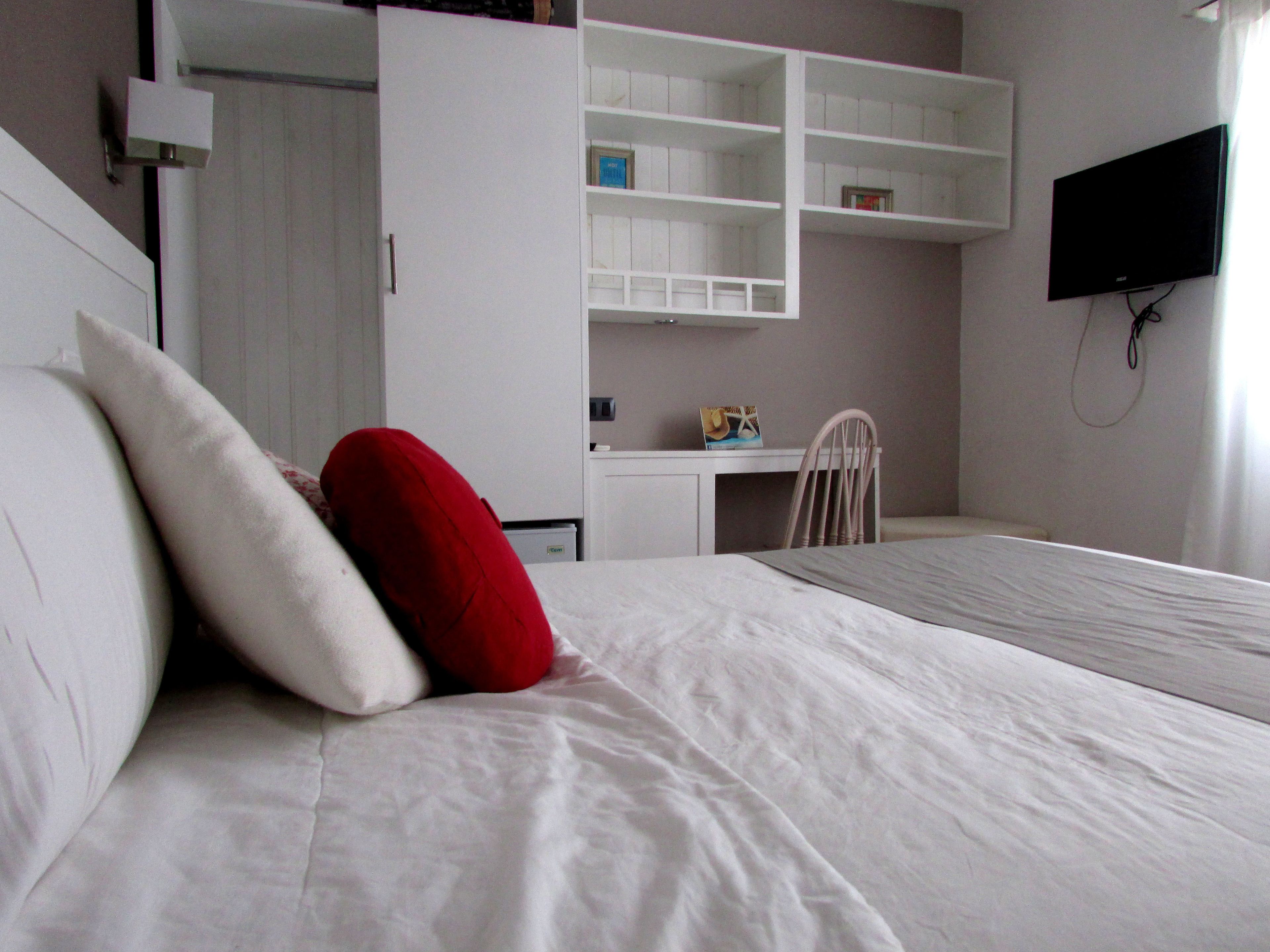 A bedroom with a bed, a desk, and a TV.